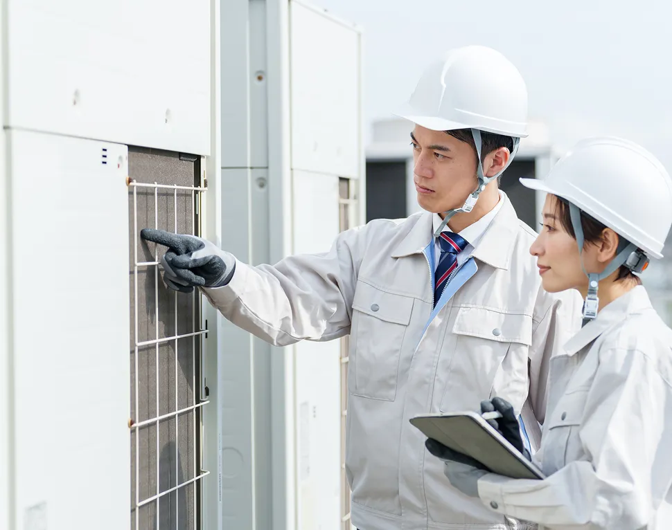 ヘルメットを着用した技術者が設備を点検し、指差し確認を行っている様子