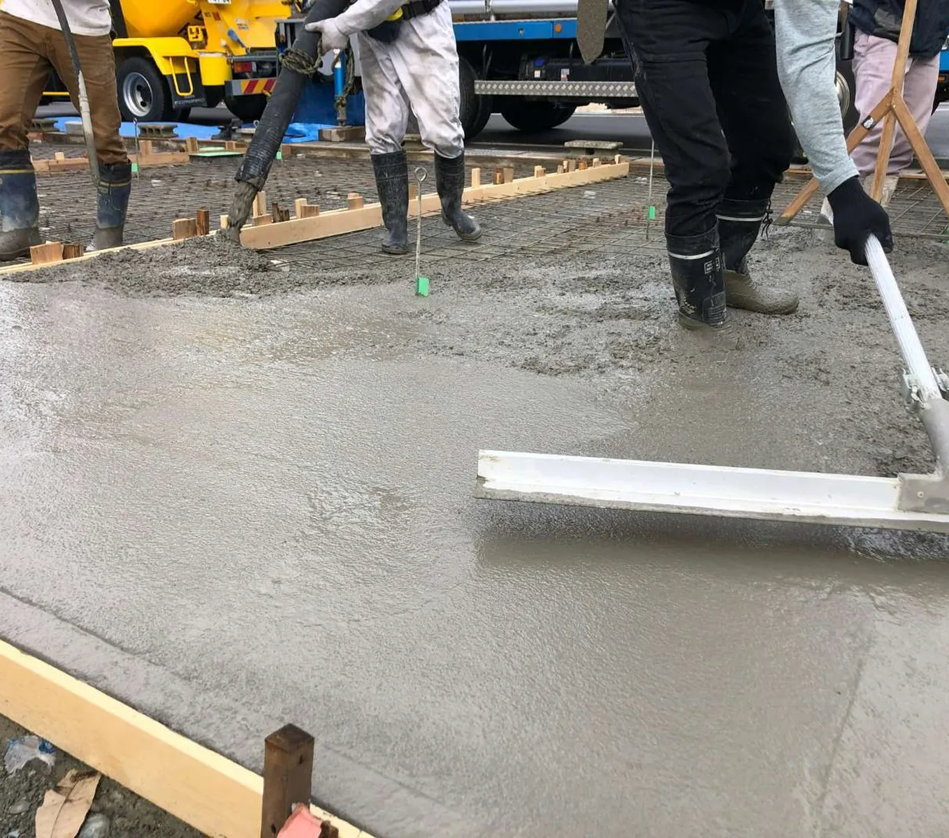 作業員がコンクリートを打設して均している現場